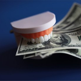 Model dentures biting a couple hundred-dollar bills