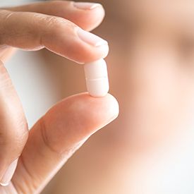 Hand holding a white antibiotic tablet pill