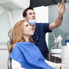 implant dentist showing seated patient X-rays