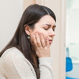 Woman holding cheek in pain