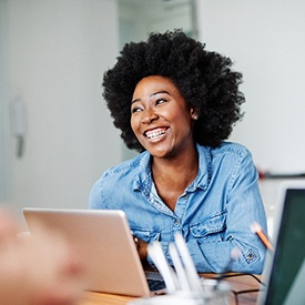 person smiling and working on their laptop