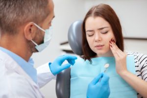 woman with a toothache talking to her emergency dentist