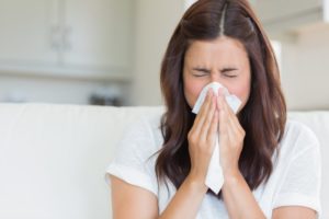 Woman sneezing into a tissue