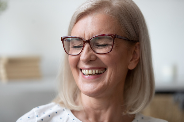 older woman with glasses smiling showing teeth