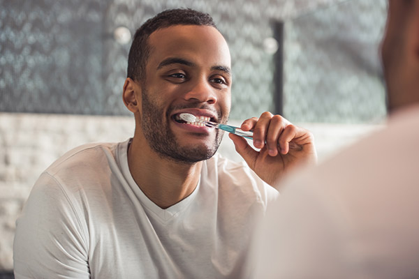 person brushing teeth to prevent dental bridge failure 