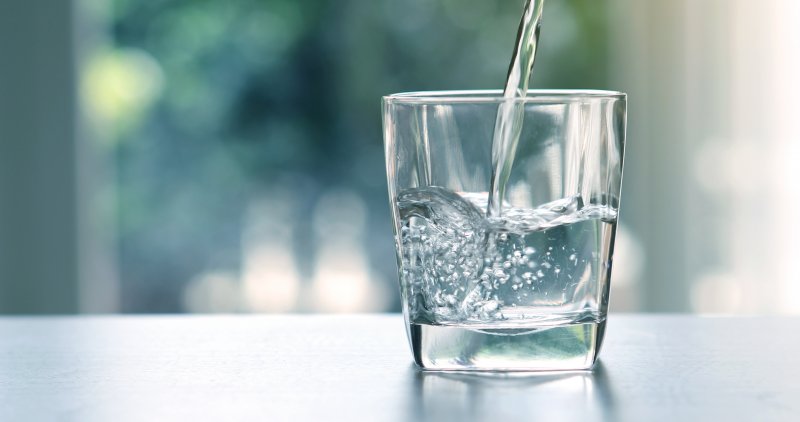 Water filling a glass on a white countertop